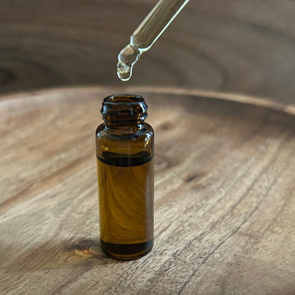 Amber glass dropper bottle of oil on a wooden surface